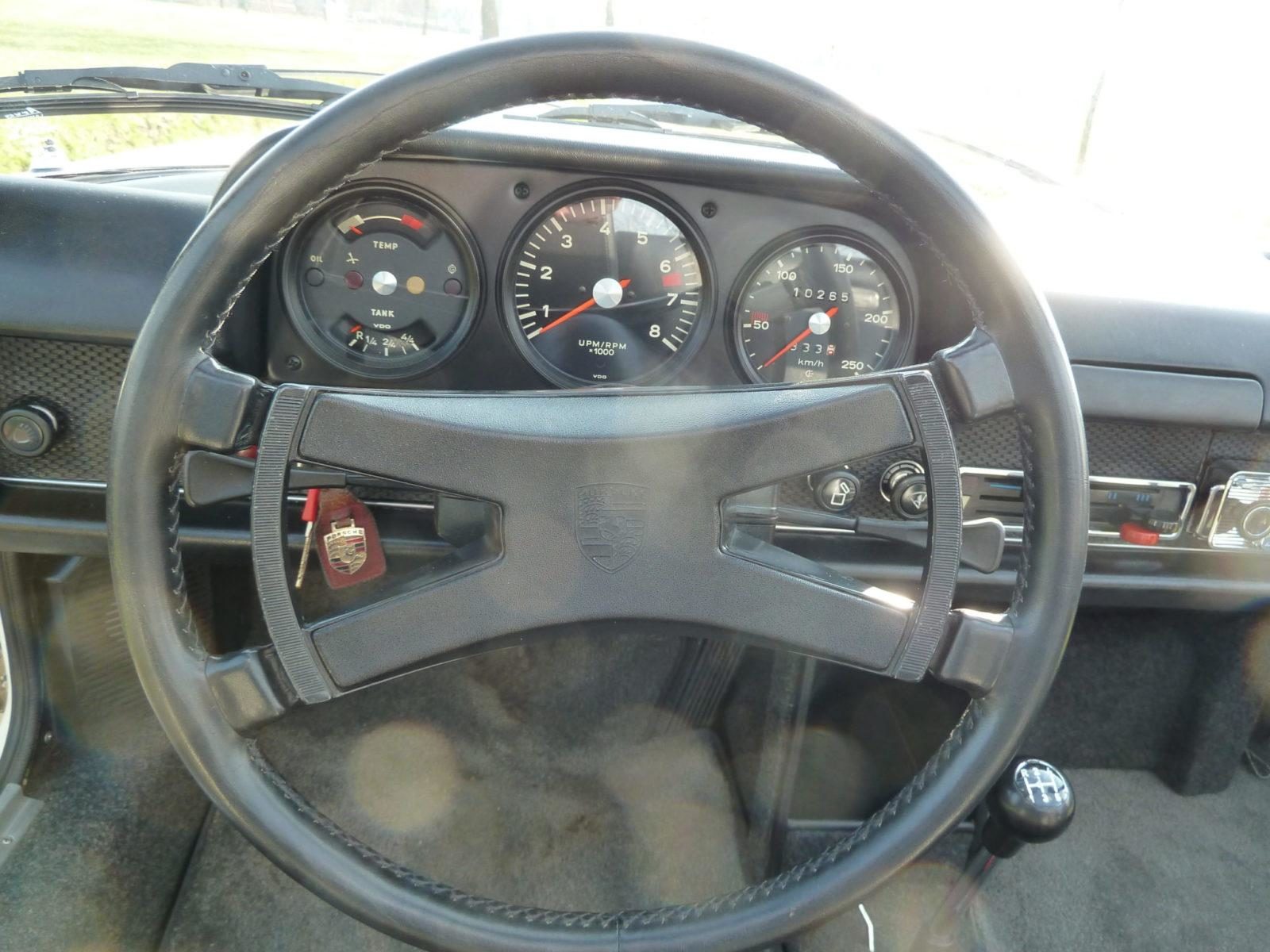 Wat is een echte? Wat met Bugatti’s, Bentleys en Laverda SFC’s gebeurde/gebeurt, dat geldt ook voor Porsche 914 zescilinders. Er zijn replica’s op de markt. Een replica kan iemand heel gelukkig maken. Maar als die replica verkocht wordt als een ‘Echte’, dan gaat het wringen in het kosten/batenplaatje. Raadpleeg dus altijd een kenner voor controle van de motor- bak- en chassisnummers plus de specificaties. De originele blokken hebben nummers die heel krap om de 6400001-6420270 zitten. Dat nummer staat (in tegenstelling tot op de 911´s) boven op het blok bij het huis van de carter ontluchting. De zescilinder motor heeft en dry sump smeersysteem. De olie zit dus niet in het carter, maar in een olietank. Die zit links in het motorcompartiment, tussen binnen en buitenscherm. De beplating van de koeling moest aangepast worden om in de motorruimte van de 914 te passen. Omdat de carburateurs teveel plek innemen zit er geen ´regen afdruip scherm´ in de motorkap. Daardoor is die een ietsepietsie lichter en daarom konden er wat lichter motorkapveren gebruikt worden. Dat is liefdevol denkwerk in de details. De transmissie van de 914/6 is een gemodificeerde 901 versie. Die is best zeldzaam, en niet optimaal. Dit soort bakken schakelde niet zo lekker. Er zijn een paar 914/zessen gemaakt met Sportomatic bakken. De Zessen hadden vijfbouts naven en de meeste werden verkocht met de optinele Fuchs velgen. Ons fotomodel heeft trouwens ook zo’n velg in de reserveband. Dat is stijlvol en scheelt gedoe met verschillende pasbouten. Er kon ook voor Mahle velgen gekozen worden. Het carrosserie van de 914/6 had een aan het schutbord aangelaste motorsteun, Bij de viercilinders zitten er twee motorsteunen aan weerszijden van het blok. De zescilinder heeft een andere stuurkolom, stuurwiel en een ander contactslot.(Op het dashboard in plaats van op de stuurkolom). De voorruitsproeier was voorzien van een elektrisch pompje in plaats van dat hij op de druk van de reserveband werkte. De toerenteller van de zescilinder gaat door tot 8.000 tpm. De snelheidsmeters hoogte aanduiding is 250 km-u. De temperatuurmeter en de tankinhoudsaanduiding zijn gecombineerd. De -6ssen hadden een handgas voorziening voor de pook. Volgens geruchten zou ook de krik van een 914/6 anders zijn.